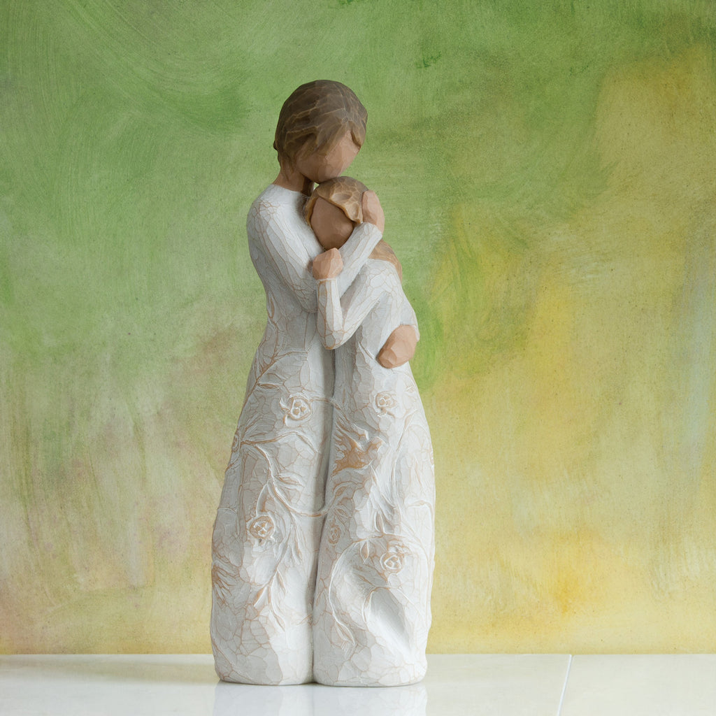 Willow Tree Close to me, 8"h hand-painted standing resin figure of woman embracing younger girl, both in cream dresses carved with intertwined vines and leaves, in front of olive green painting