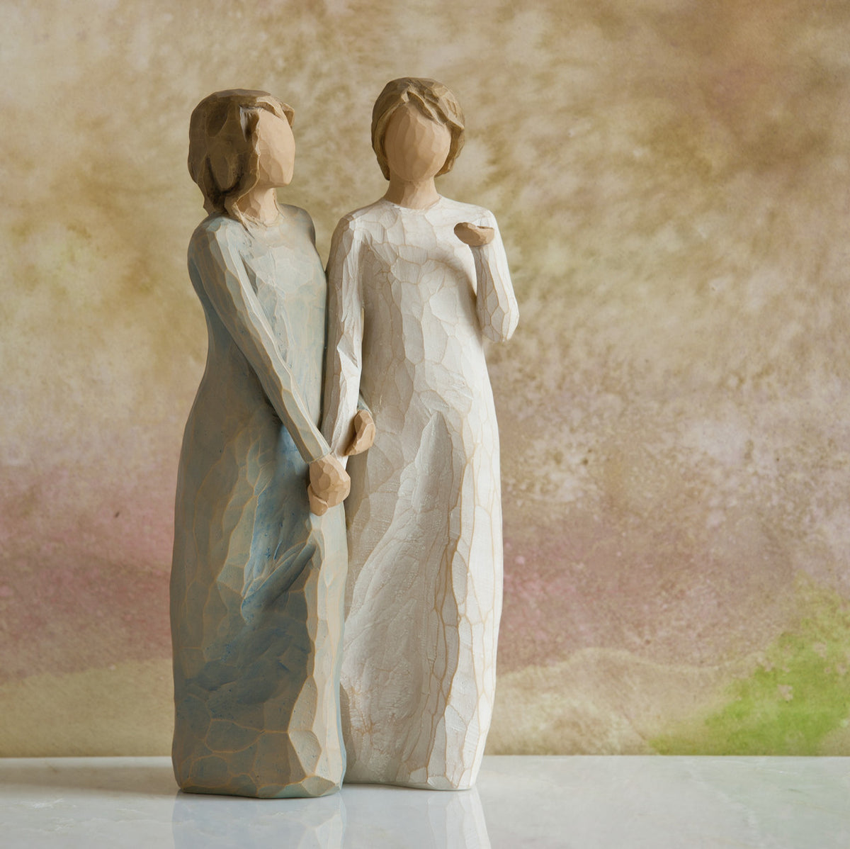 Willow Tree My sister, my friend, 8.5”h hand-painted figure of two females standing next to each other, arms/hands connected, one in cream dress, one in blue/gray dress, in front of dusty pink painting