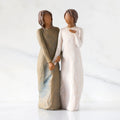 Front view: Figure of two women with darker skin tones in different colored dresses, standing arm in arm