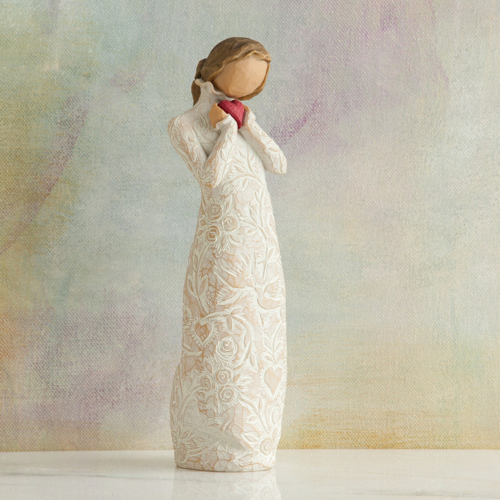 Willow Tree Je t'aime (I Love You), 8.5"h hand-painted standing resin figure holding red heart in cream dress with ruffled neck and carved with hearts, flowers and birds, in front of muted painting