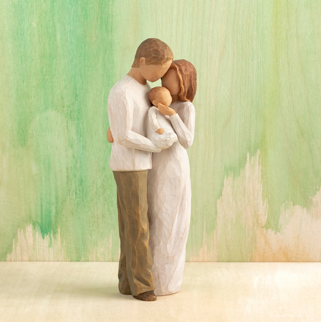 Willow Tree Our Gift, 8.5”h hand-painted resin figure of standing couple holding baby between them, all in neutral clothing, in front of green painting