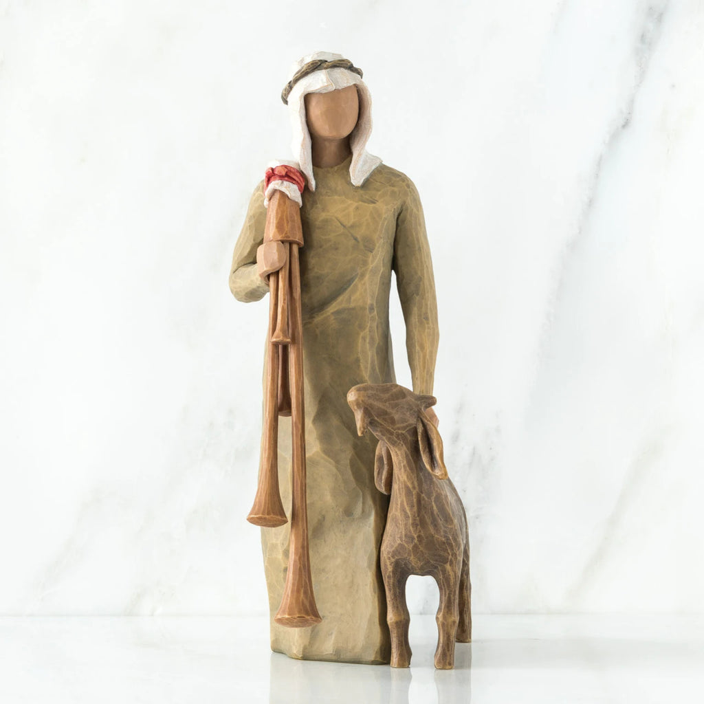 Wise man figurine standing in light brown attire with white headpiece, brown sheep at his feet