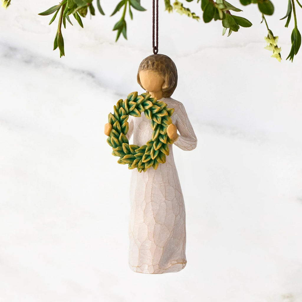 Figure in cream dress, holding green wreath of magnolia leaves in front of her. Hook and loop affixed to figure's head