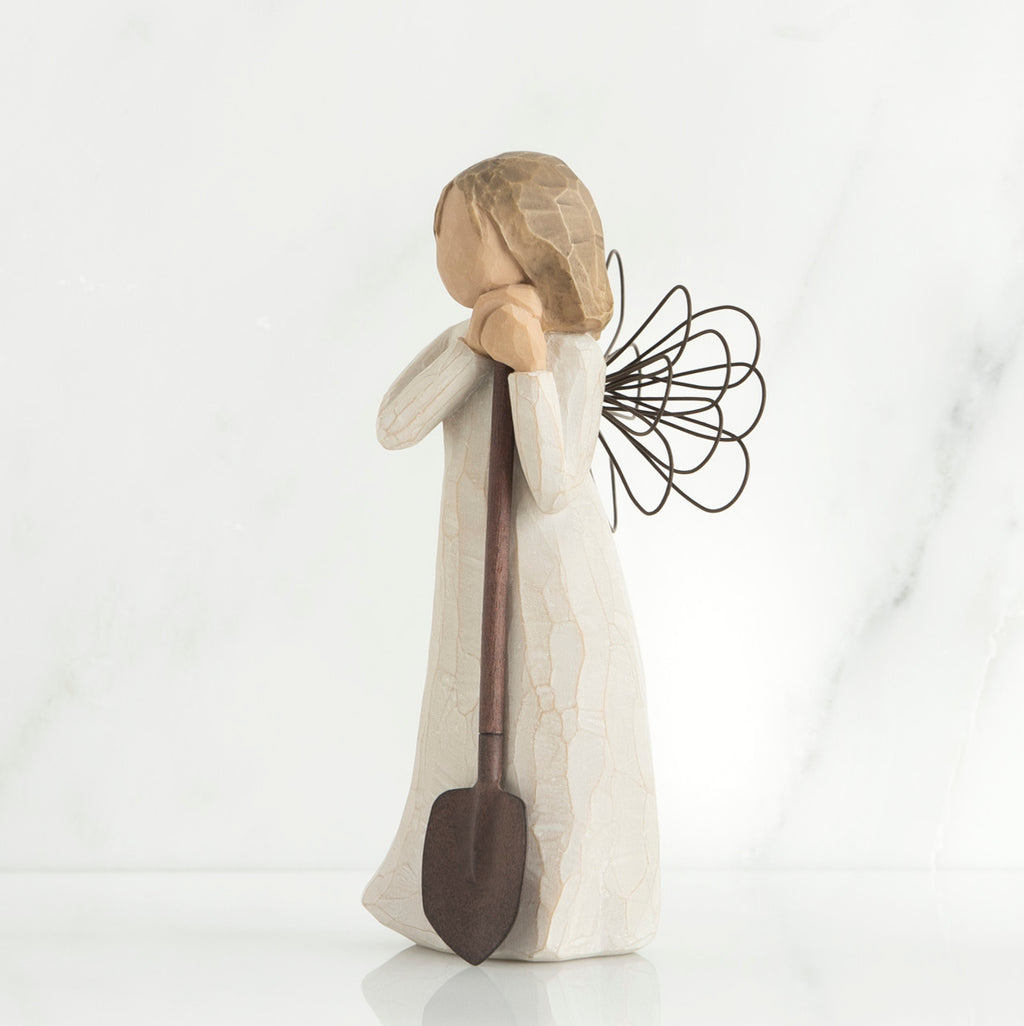 Young brunette girl figurine in white dress holding brown shovel
