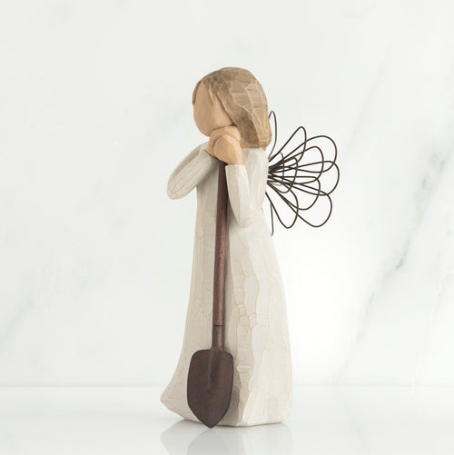 Young brunette girl figurine in white dress holding brown shovel