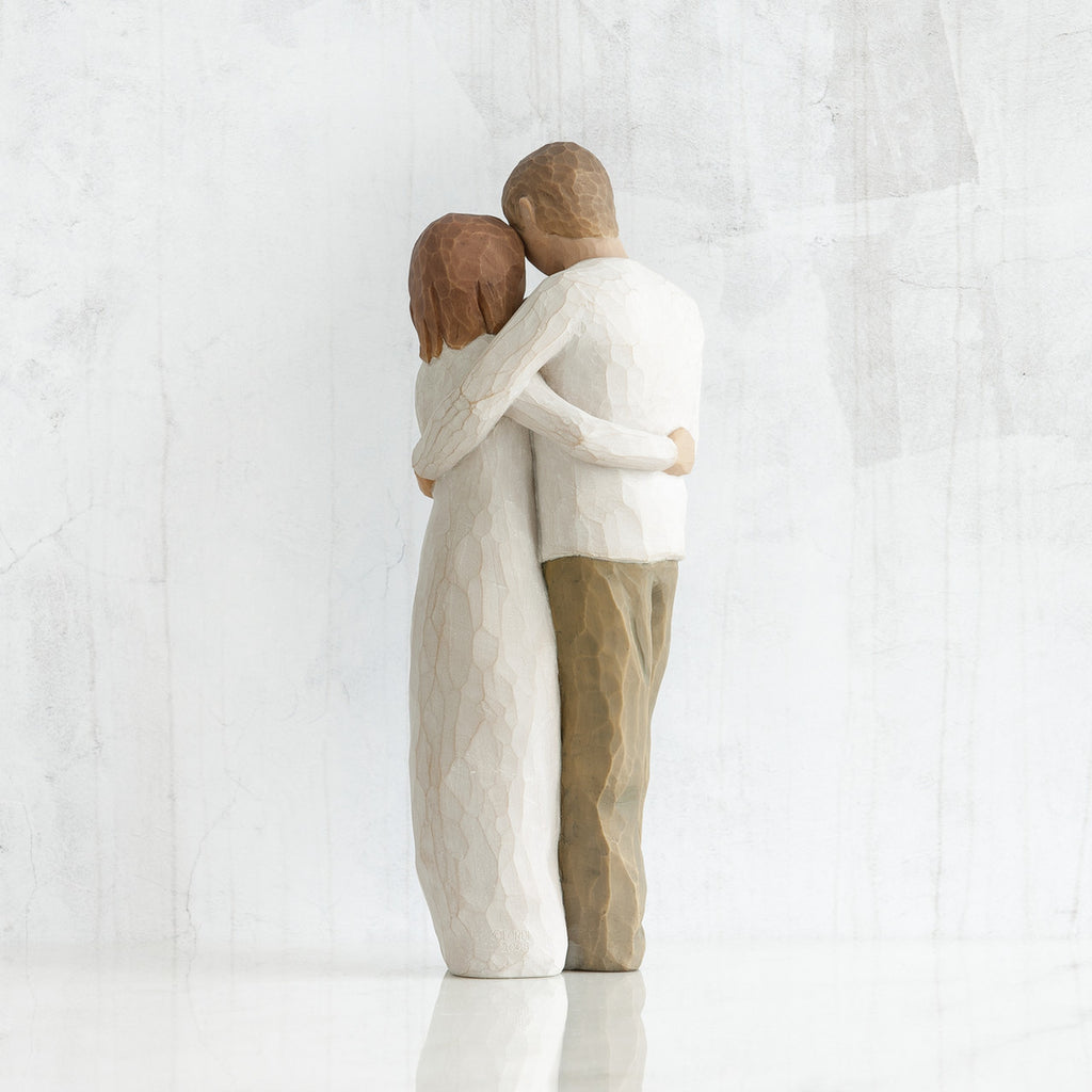 Man and woman figurines - back view - hugging another