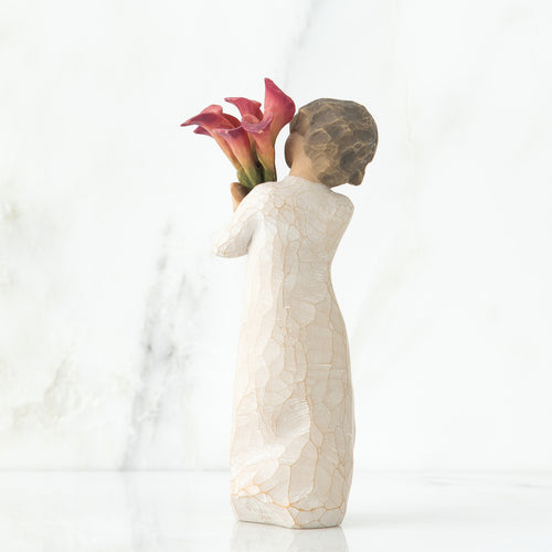 Back view of little girl with short brown hair holding a cluster of red calla lilies