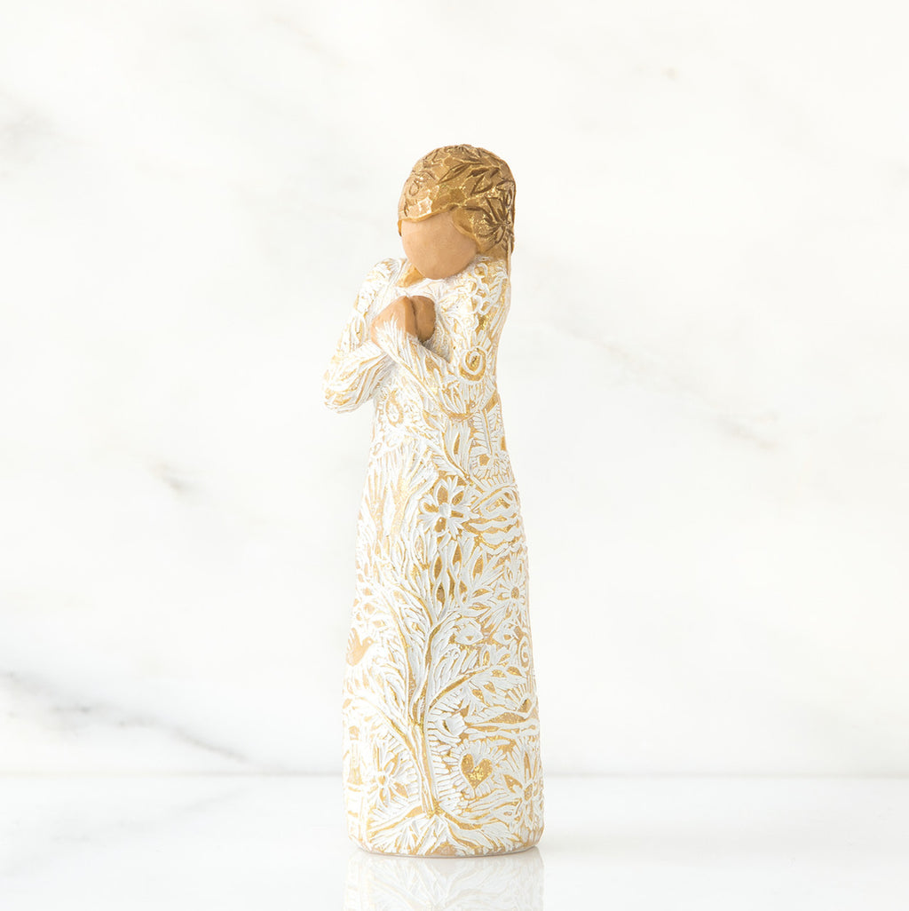 Gold haired woman in white/gold dress facing forward with arms to her chest