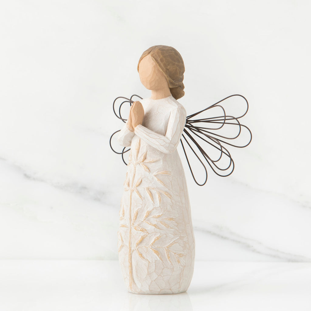 Side view of brunette angel figurine in white dress holding hands in prayer with black wire wings