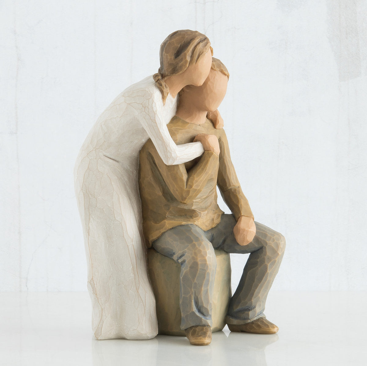 Close view of woman figurine in white dress with arms around man figurine in brown shirt