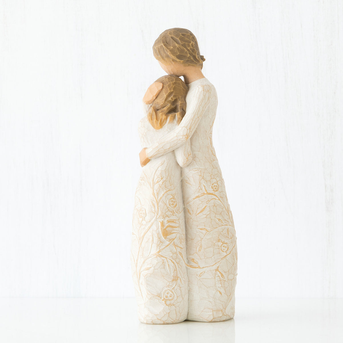 Side view of two brunette girls in white dresses hugging another