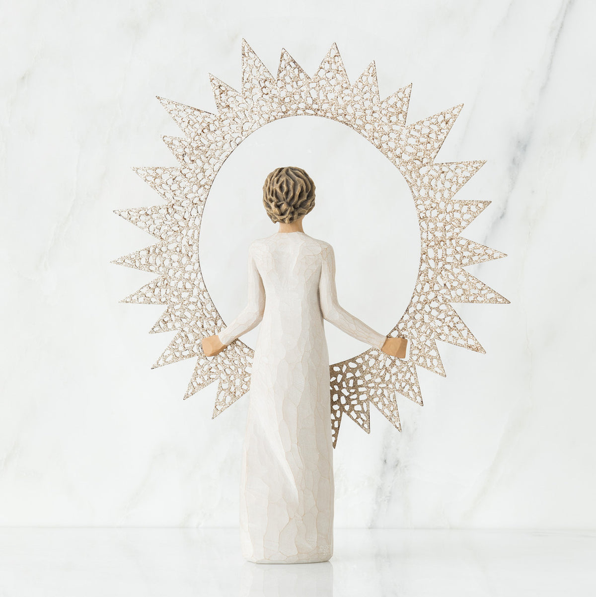Back view of brunette girl figurine in white dress holding sun figurine up