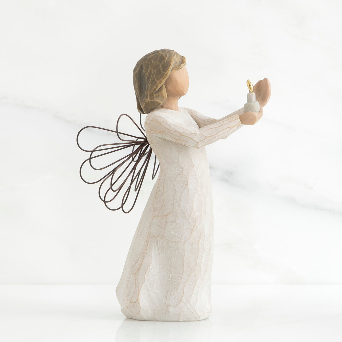 Side view of brunette girl figurine in white dress with brown wire wings holding up candle