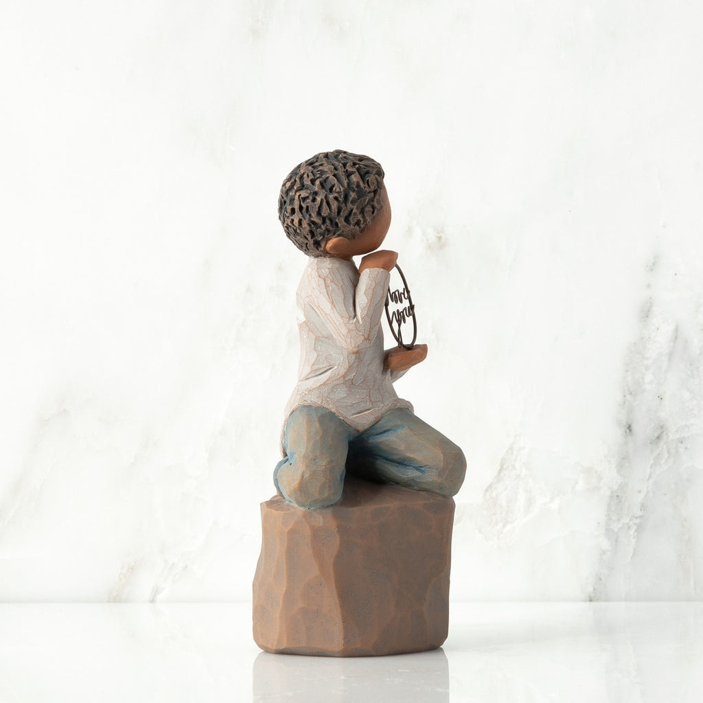 Left view: Figure of darker-skin child, kneeling on rock, holding wire circle with ‘love you’ written in wire