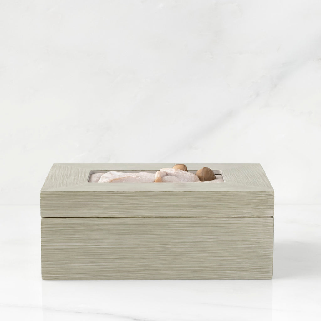 Side view: Light gray rectangular wood box with hinged lid, carving on lid of female and child embracing in cream dresses