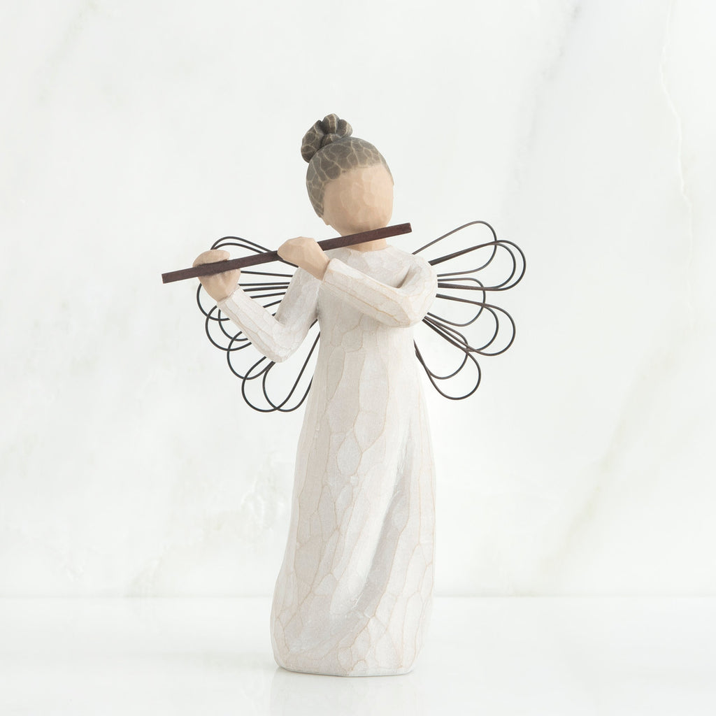Faceless angel figurine wearing white dress and black wire wings playing black flute