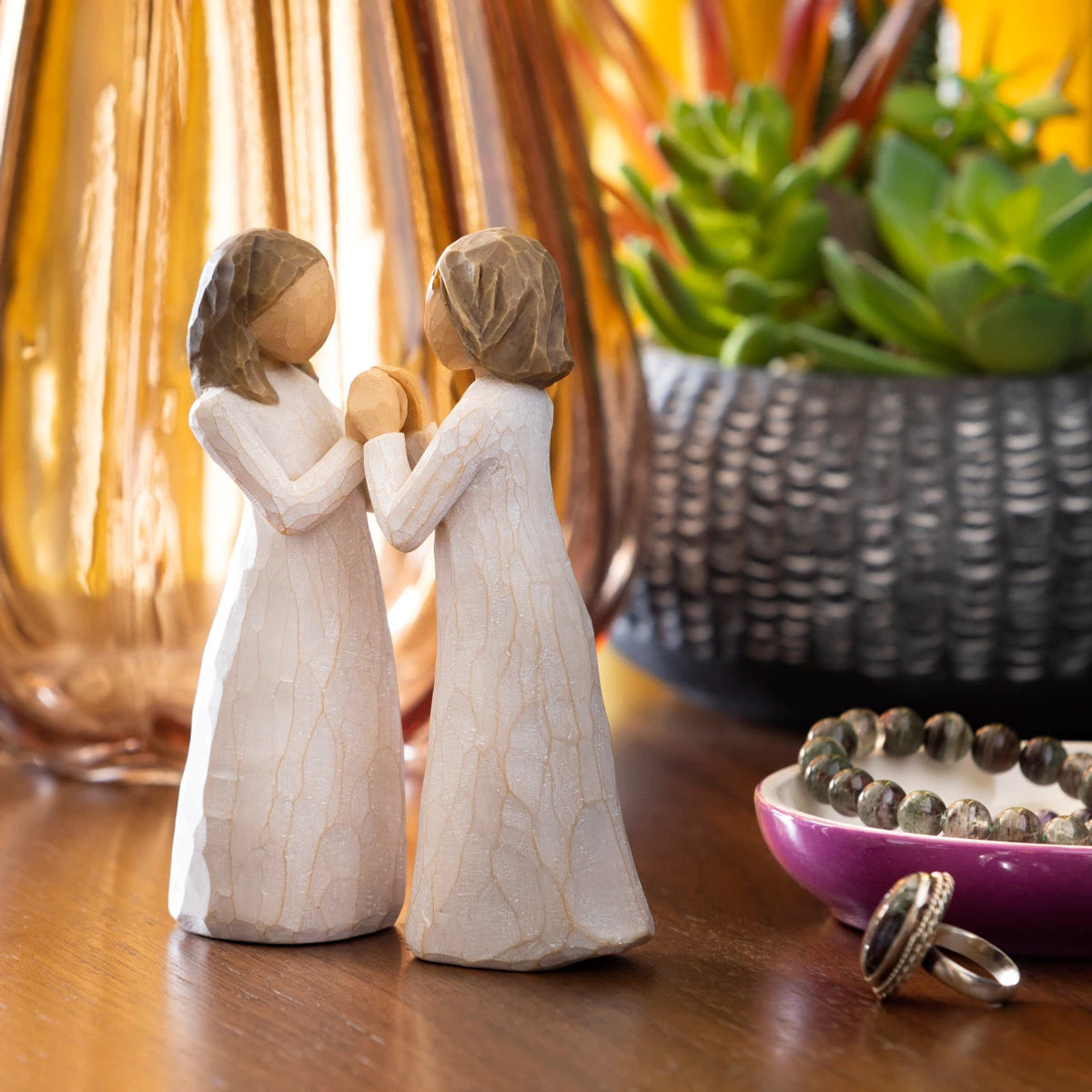 Willow Tree Sisters by Heart, two separate 4.5”h hand-painted standing resin figures in cream dresses with hands that fit together, on dresser with jewelry and succulent