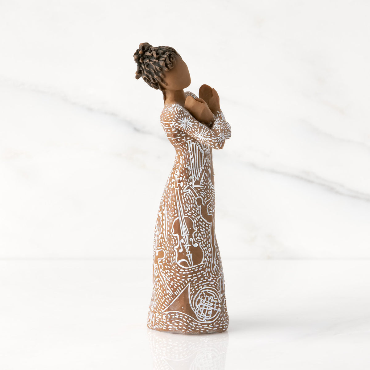 Facing right: Darker-skin figure carved with contrasting pattern of white musical symbols, instruments, dancing forms
