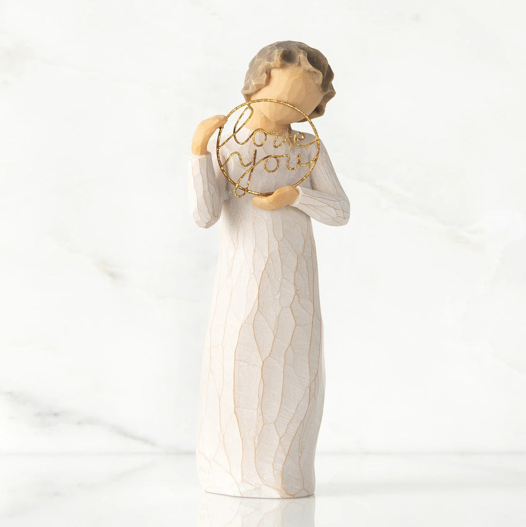 Front view, standing female figure in cream dress, holding gold wire circle in which is written 'love you'