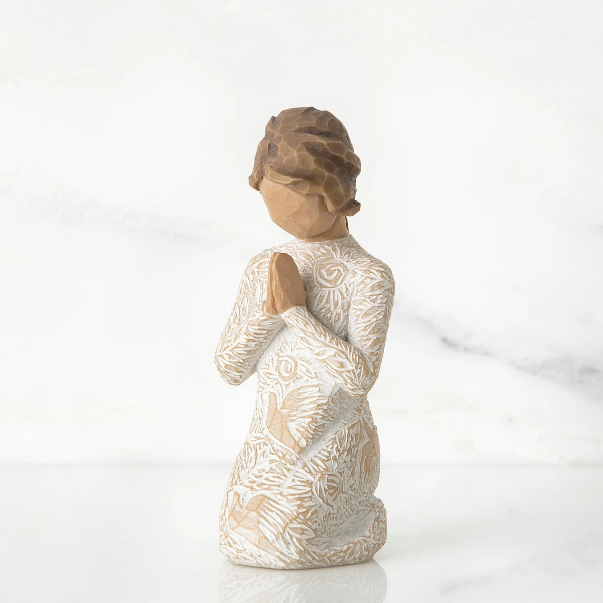 Small faceless girl figurine wearing white/tan bird design dress, kneeling and praying