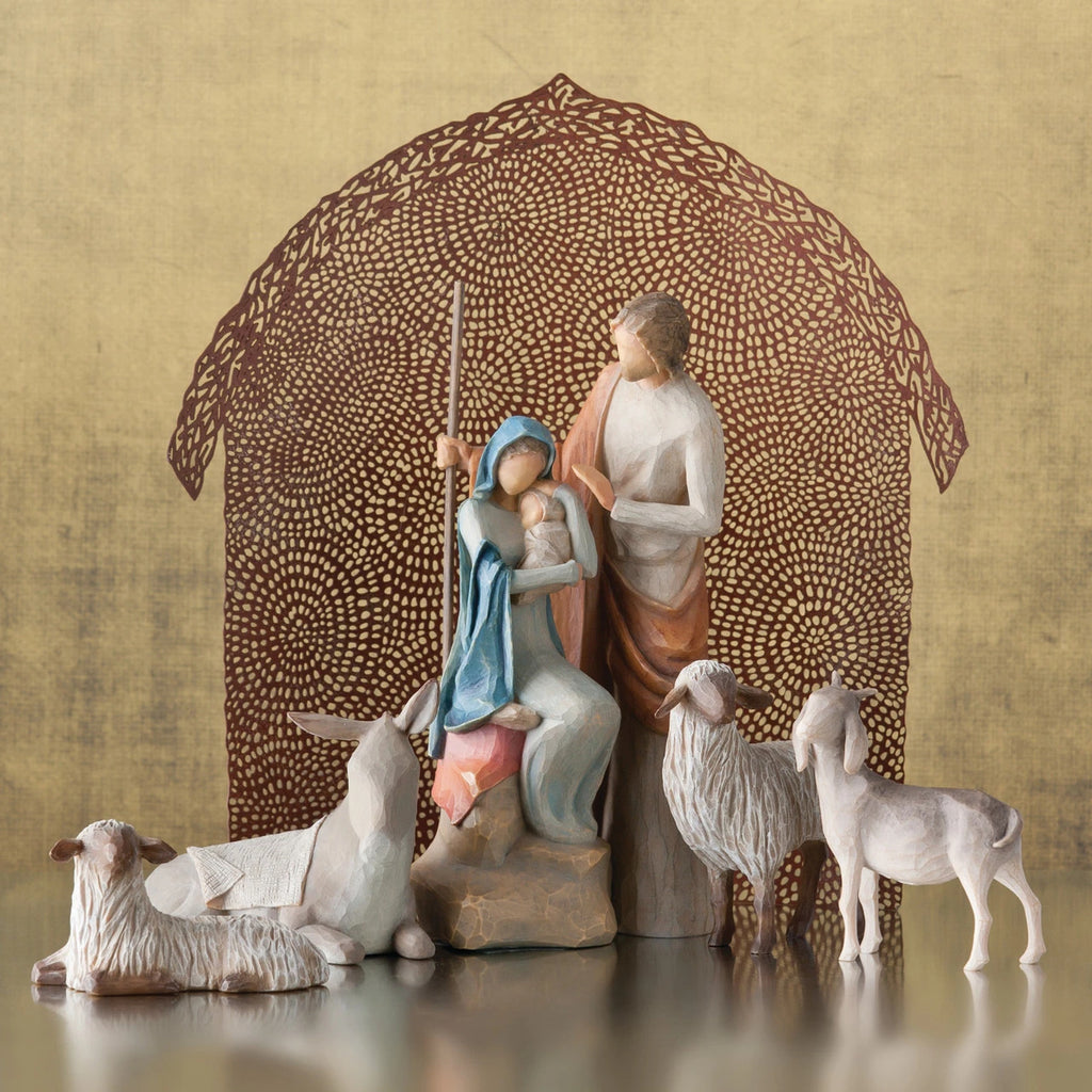 Mary and joesph figurines holding baby with four sheep figurines around them - brown sheer barn paper behind them